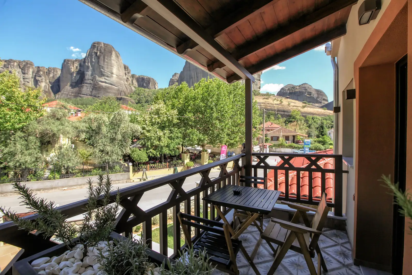 A suite balcony with a small table facing the Meteora rocks