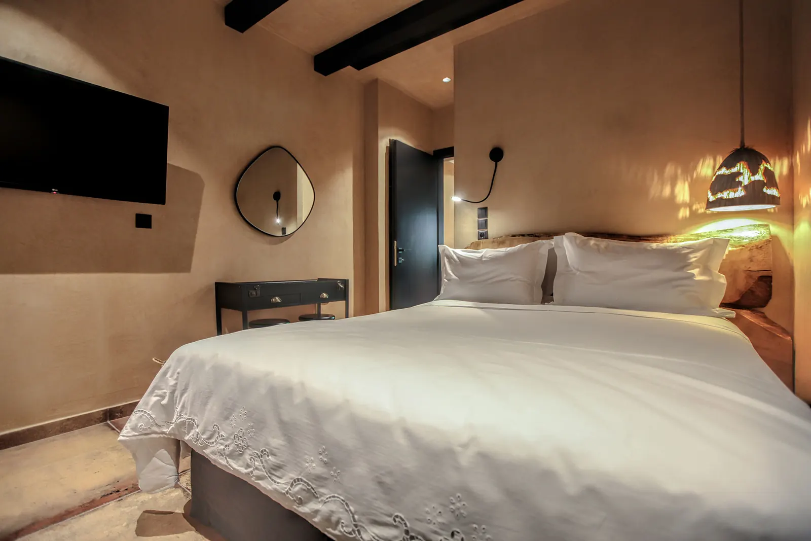 A suite bedroom with warm lamps and dark wooden beams