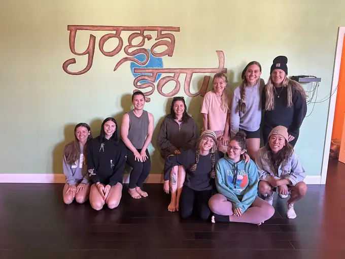 A graduating YogaSoul teacher training cohort in front of the YogaSoul sign