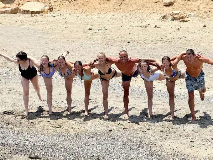 Retreat guests lined up arm in arm on the sand, Koufonisia 2026