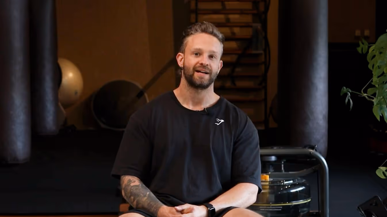 Man in zwart shirt zit in sportruimte met fitness-apparatuur