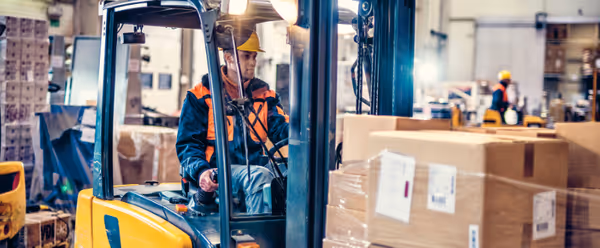 a man driving a forklift with boxes