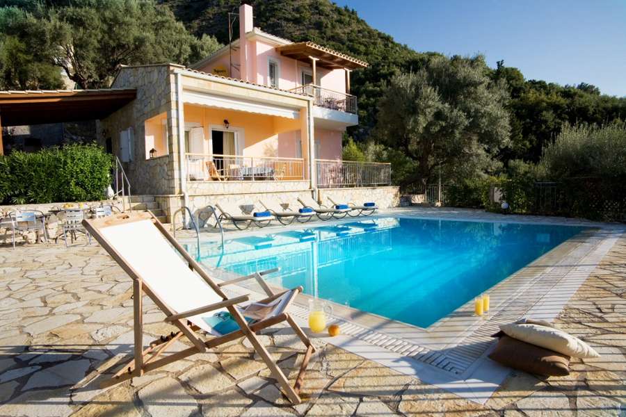 A balcony of a summer holiday home by the beach with an open umbrella in the middle of the image.