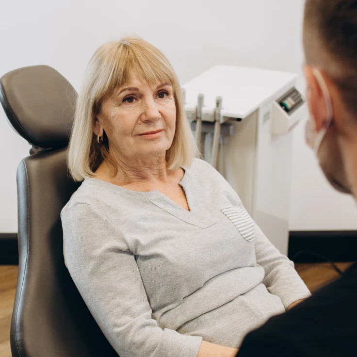 A woman sitting in a chair with a man looking at her.