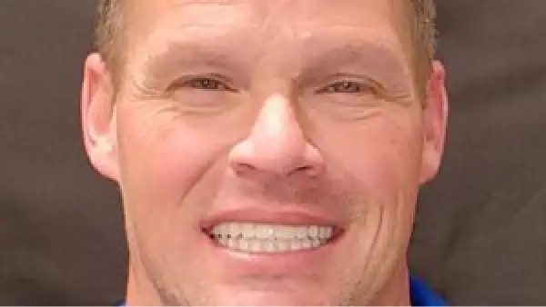 A close up of a person wearing a blue shirt smiling.
