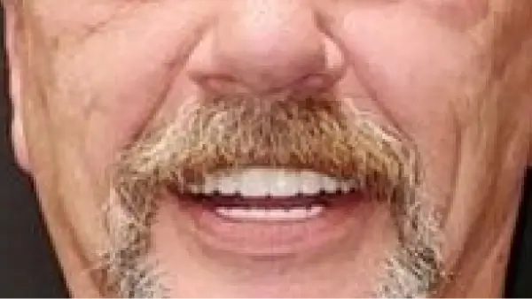 A close up of a man with a mustache smiling.