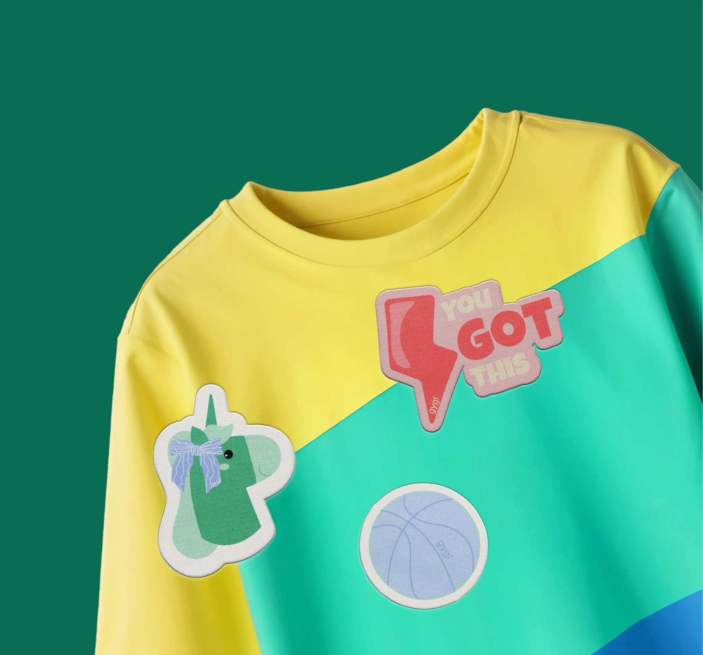 Yellow, teal, and blue color-blocked shirt with a green unicorn patch, a red patch that says 'you got this,' and a blue basketball patch.