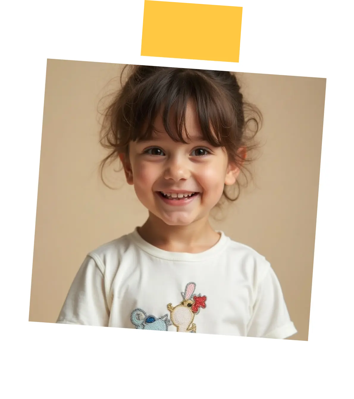 Smiling young girl with brown hair and bangs wearing a white shirt with cartoon animals.