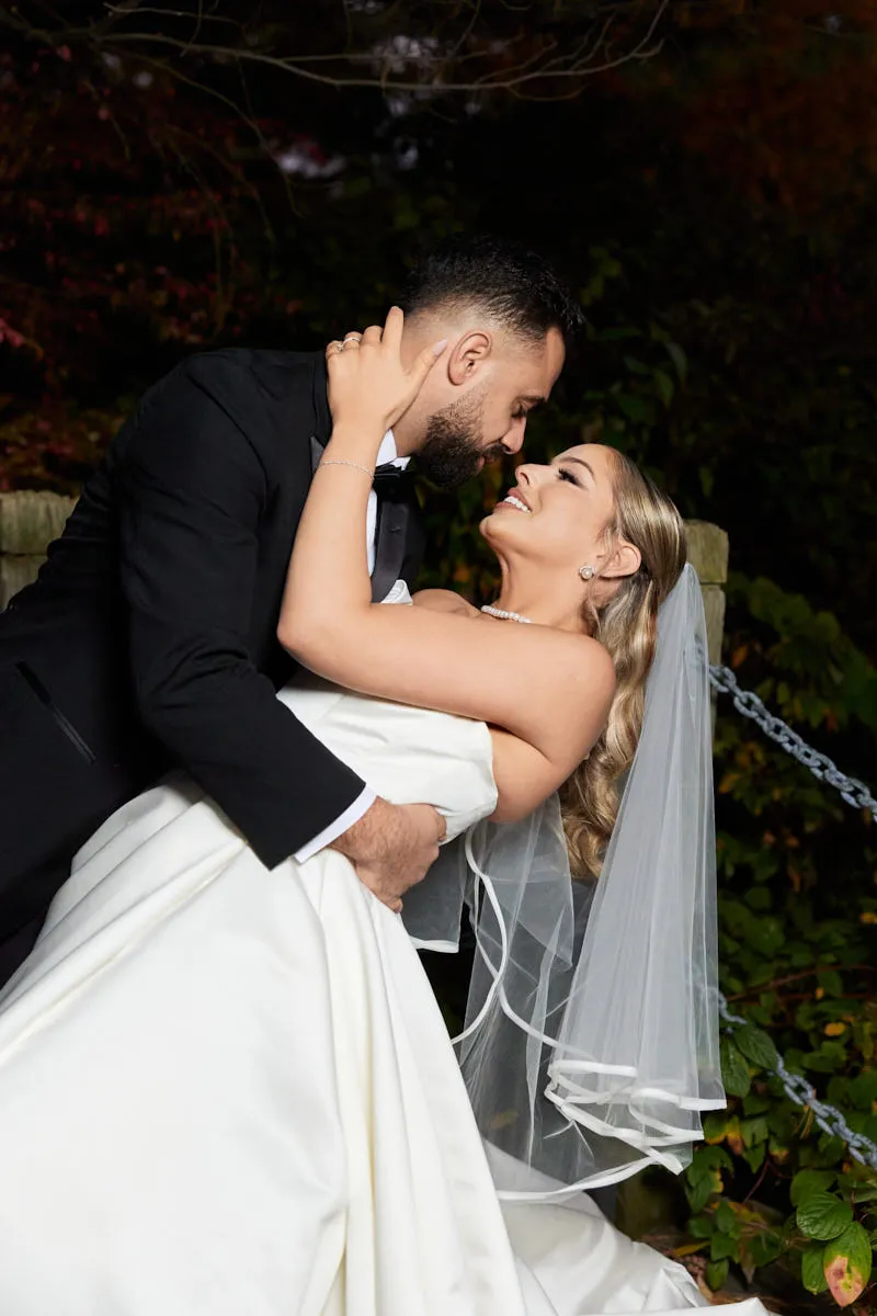 Le marié fait basculer la mariée pour l'embrasser devant un feuillage d'automne, le jour de leur mariage