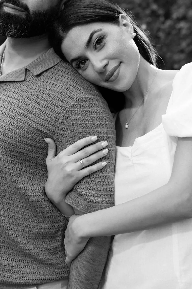 Portrait de fiançailles en noir et blanc : une femme appuie la tête sur l'épaule de son fiancé