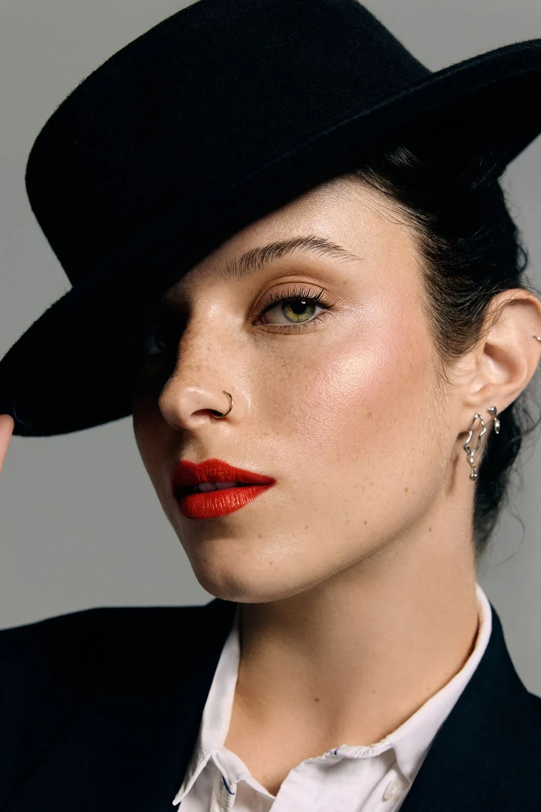 Portrait mode d'une mannequin coiffée d'un chapeau noir à large bord, rouge à lèvres rouge