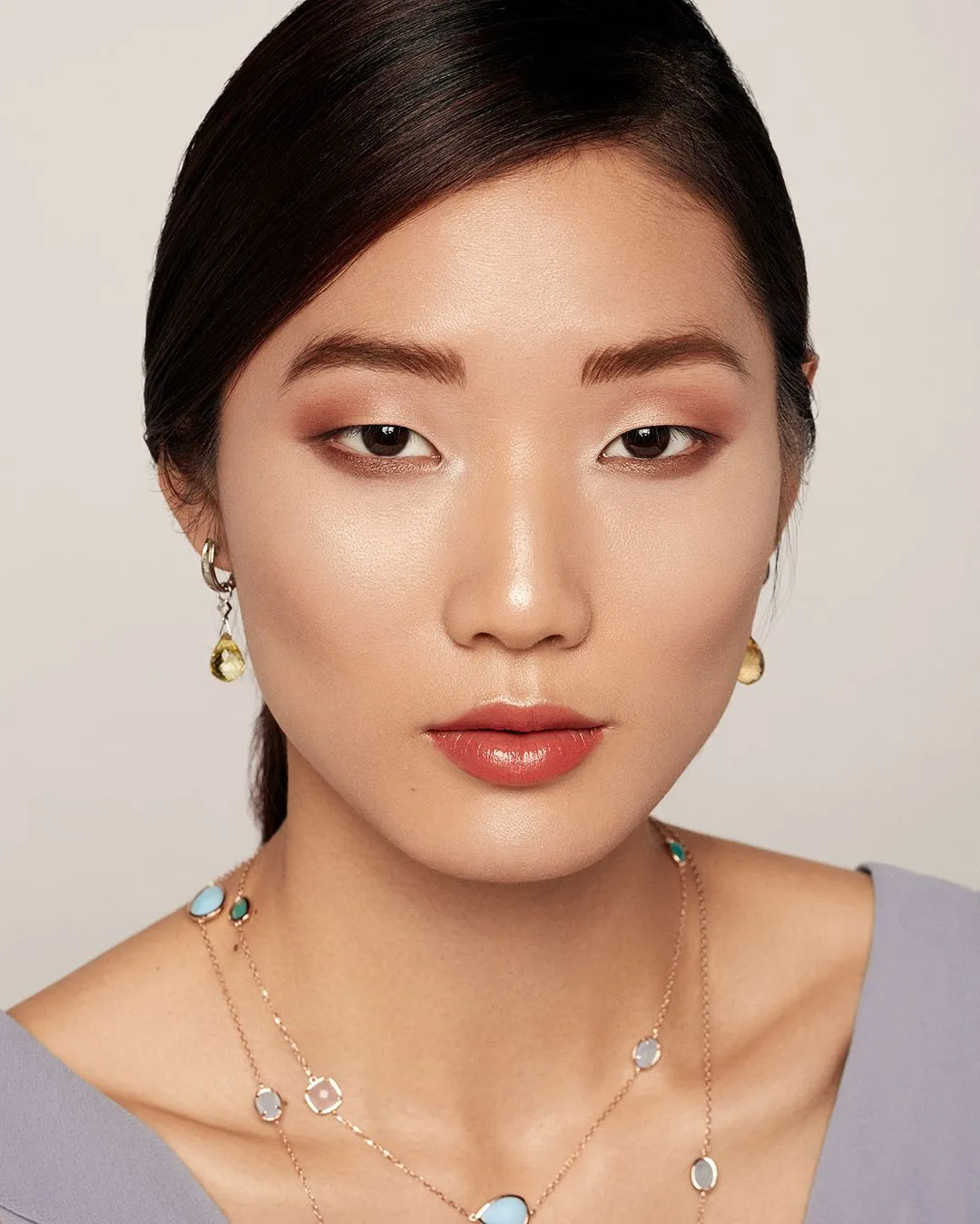 Portrait beauté d'une mannequin aux cheveux lissés, maquillage naturel et bijoux dorés