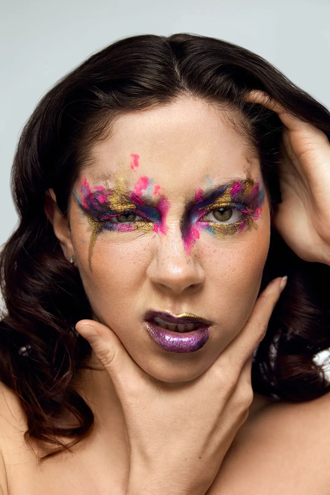 Portrait maquillage créatif d'une mannequin aux yeux peints de rose et d'or et aux lèvres violettes