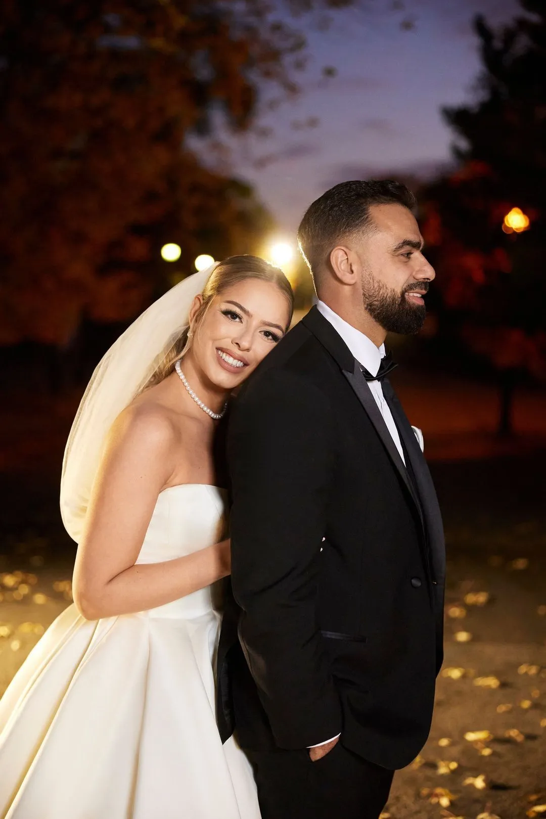 Bride and groom posing at night in a park, lit by a warm glow