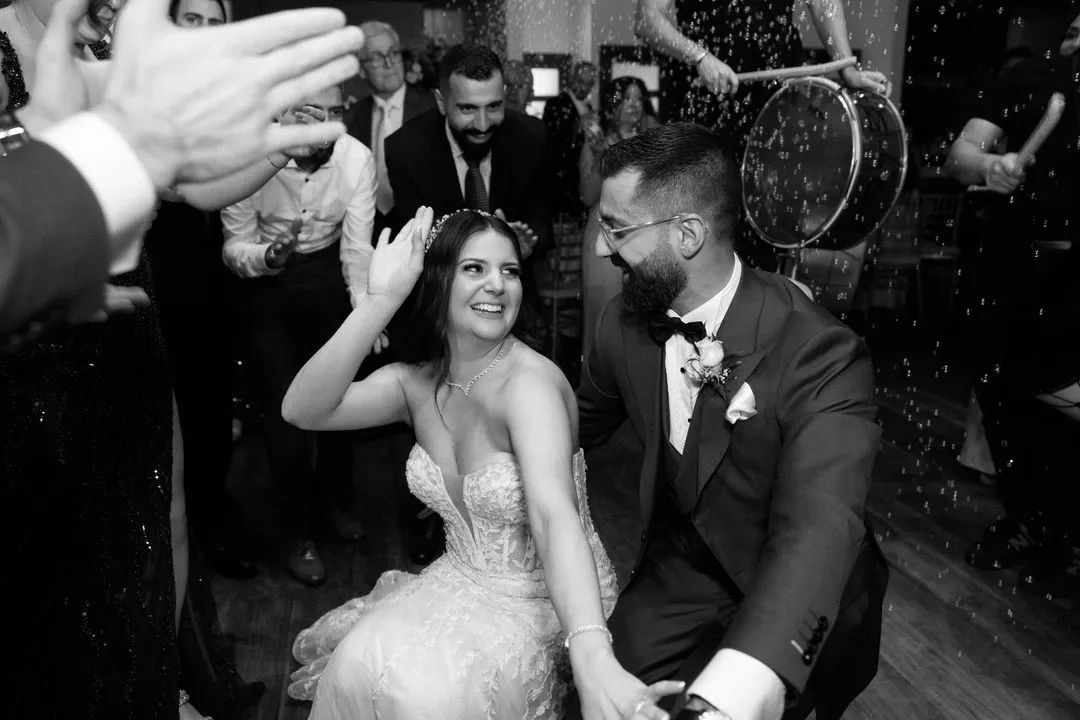 Black-and-white photo of the bride and groom dancing with guests at the reception