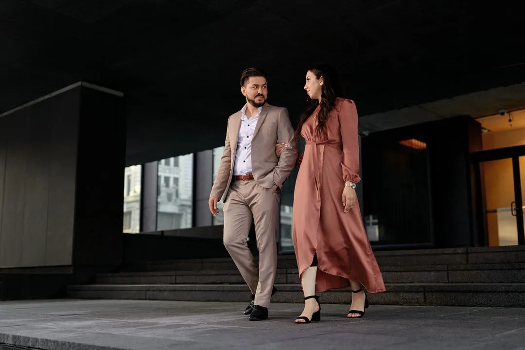 Couple de fiancés marchant ensemble sous un édifice moderne au centre-ville