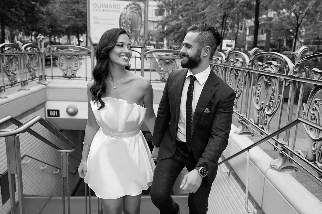 Photo en noir et blanc d'un couple montant l'escalier de l'entrée Art nouveau du métro Square-Victoria, à Montréal