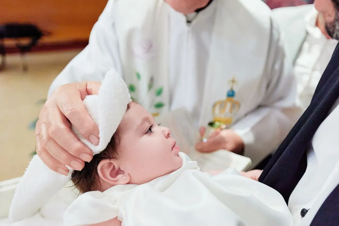 Gros plan du prêtre séchant la tête du bébé avec un linge blanc après le baptême