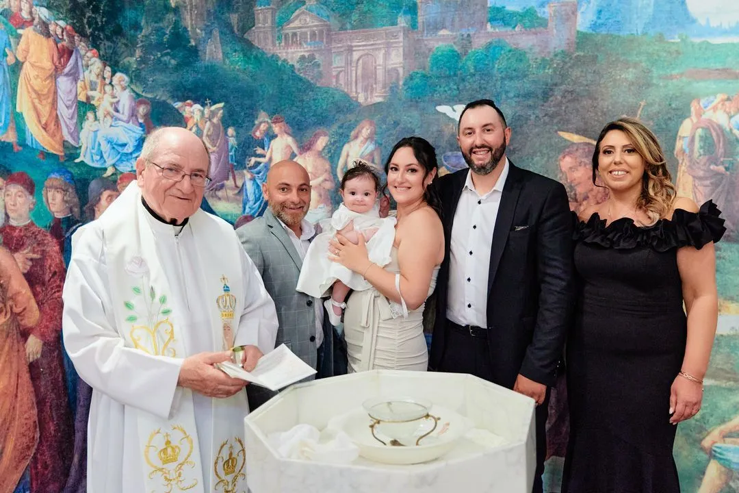 Portrait de famille avec le prêtre et le bébé baptisé près des fonts baptismaux