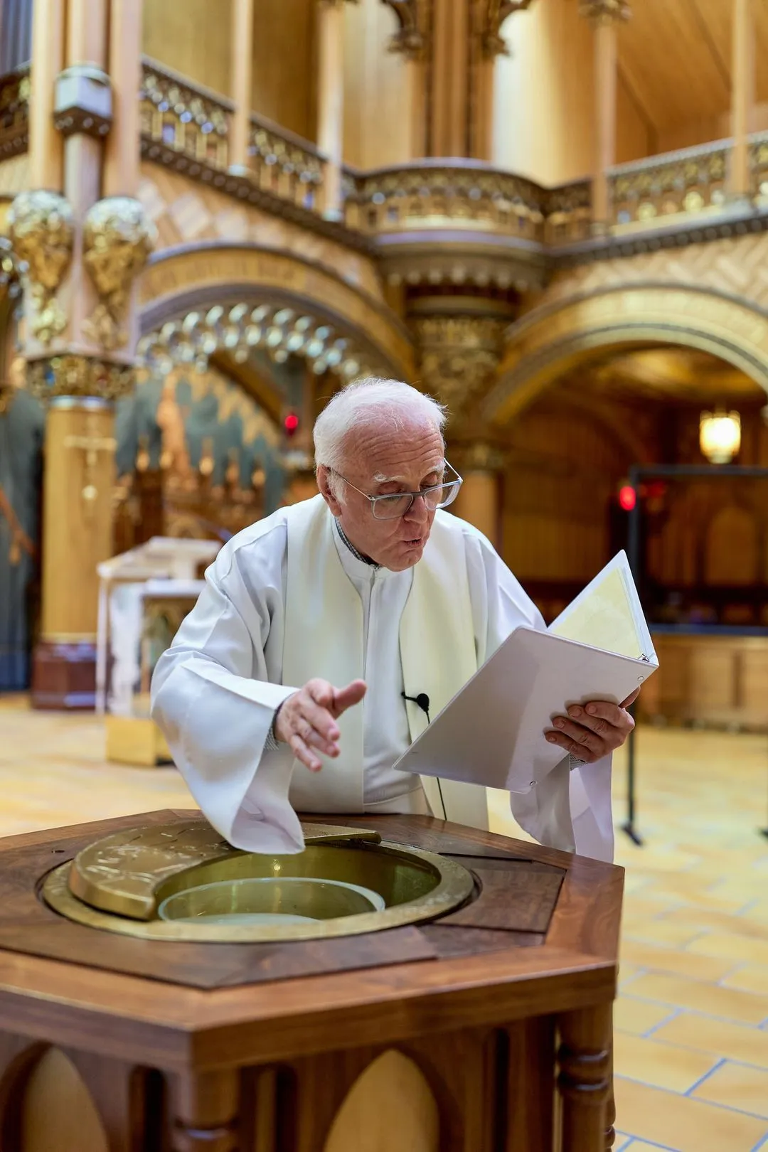 Le prêtre lit le rituel du baptême près des fonts baptismaux dans une chapelle ornée