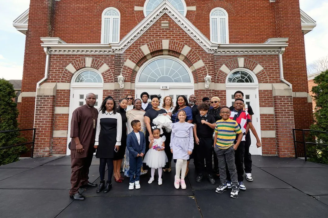 Photo de groupe de la famille devant une église de briques rouges après le baptême