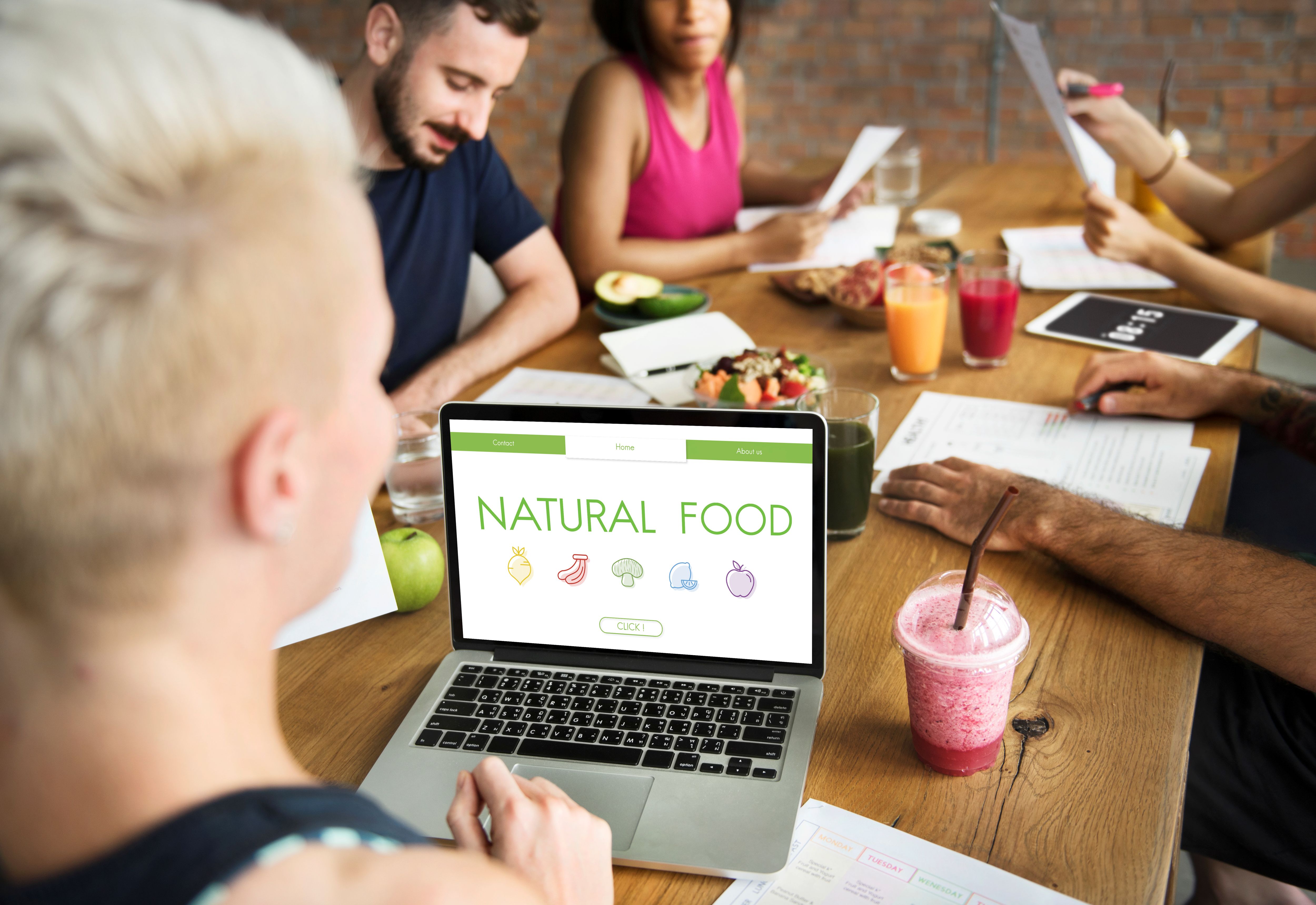 People sitting around the table with a Laptop working on the website 