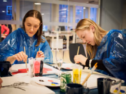 Två kvinnor sitter och målar.