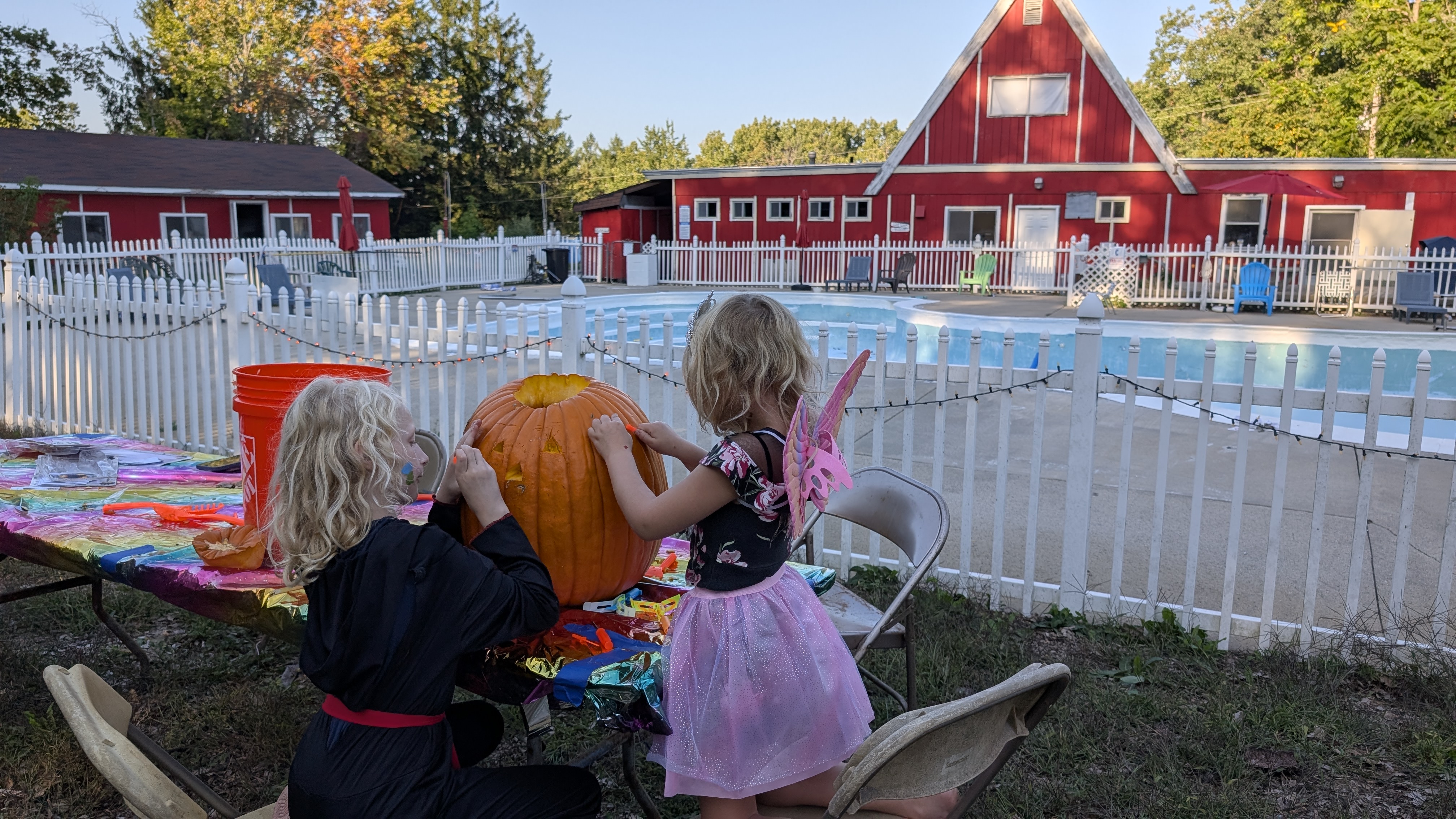 2 girls in Halloween costumes carve pumpkins during Halloween weekends at Paul Bunyan Campground
