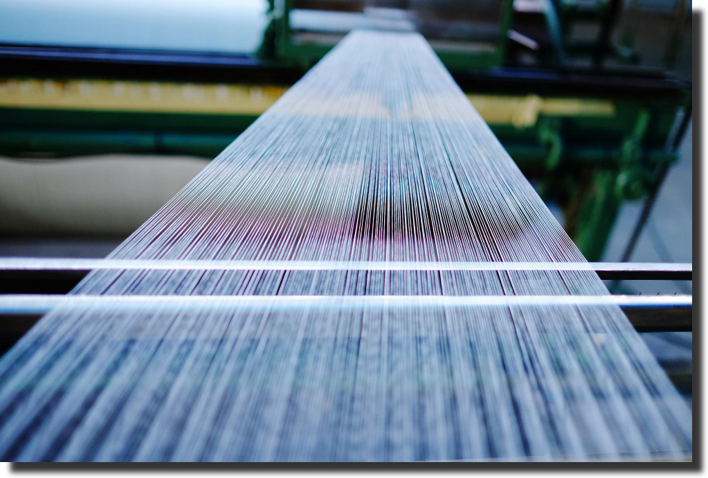Long fiberglass rovings drawn through a creel, illustrating raw glass fibers and the fiberglass vs carbon fiber weight difference at source.