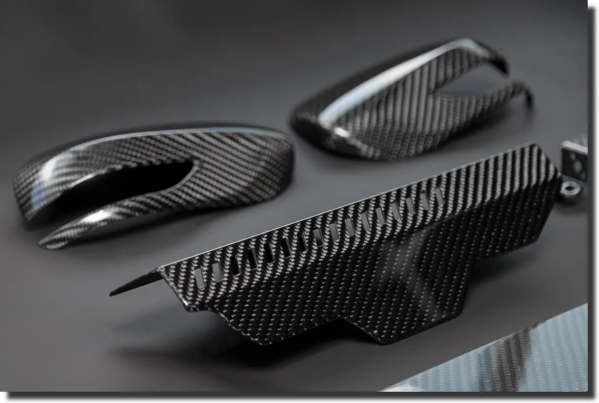 Finished carbon fiber components on a workbench, showing what is DFM when aligning design manufacturing choices with tooling and production realities.