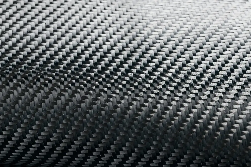 Close-up woven carbon fiber surface representing the prepreg carbon fiber process for consistent structural parts.