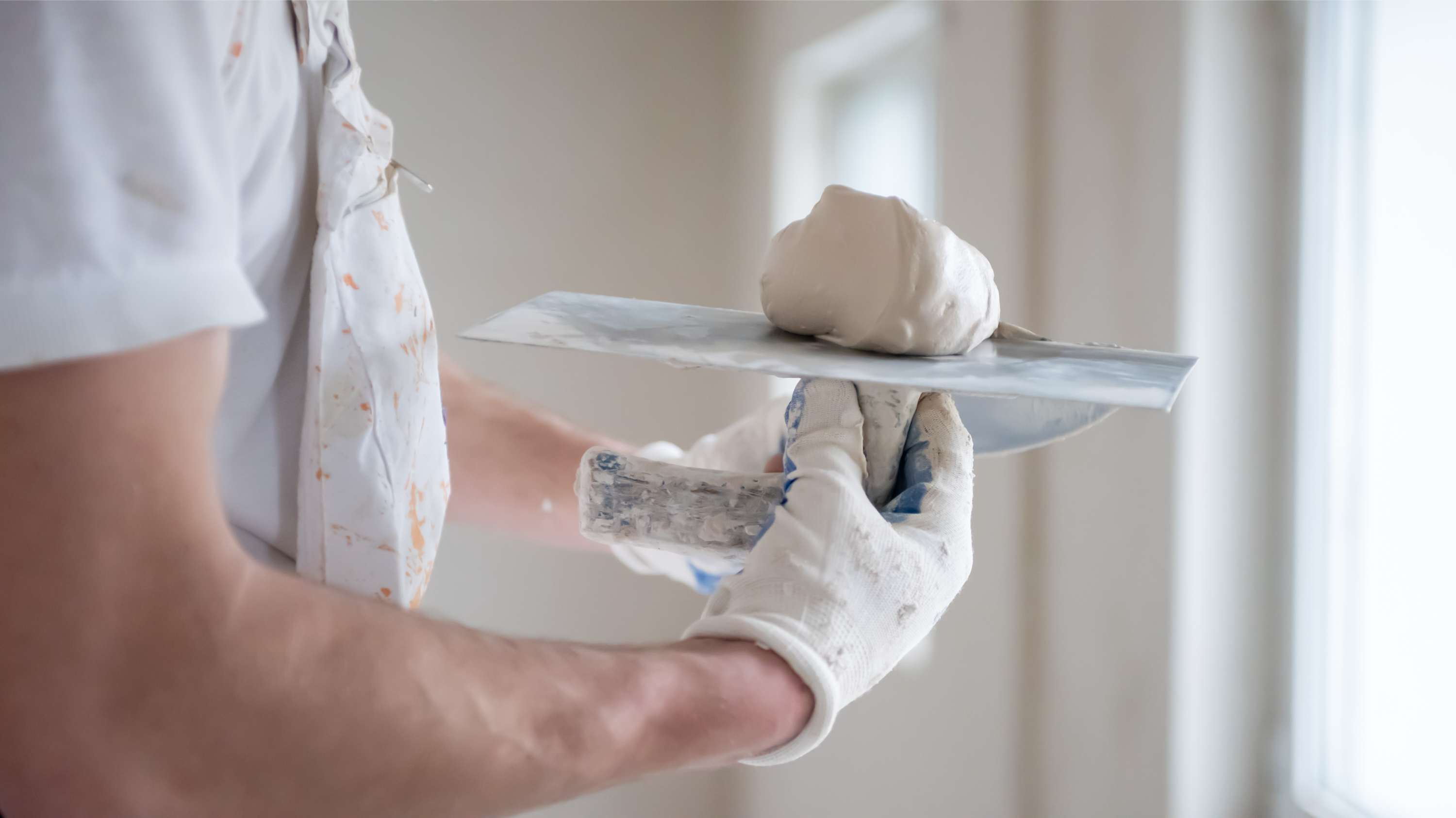 Photo of a hand holding a roller with plaster