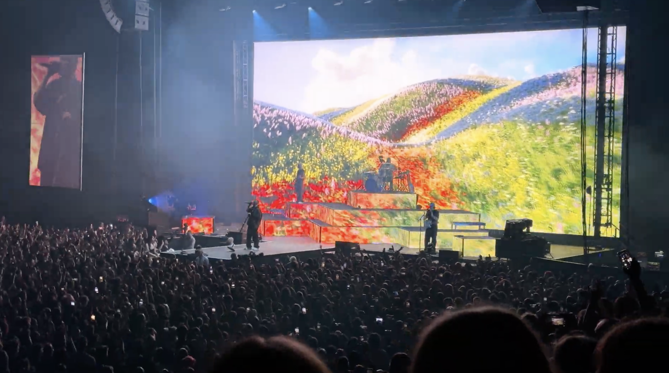 Concert stage with colorful landscape projection and packed crowd
