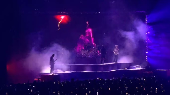 Rock band performing on smoky stage with dramatic purple and red lighting