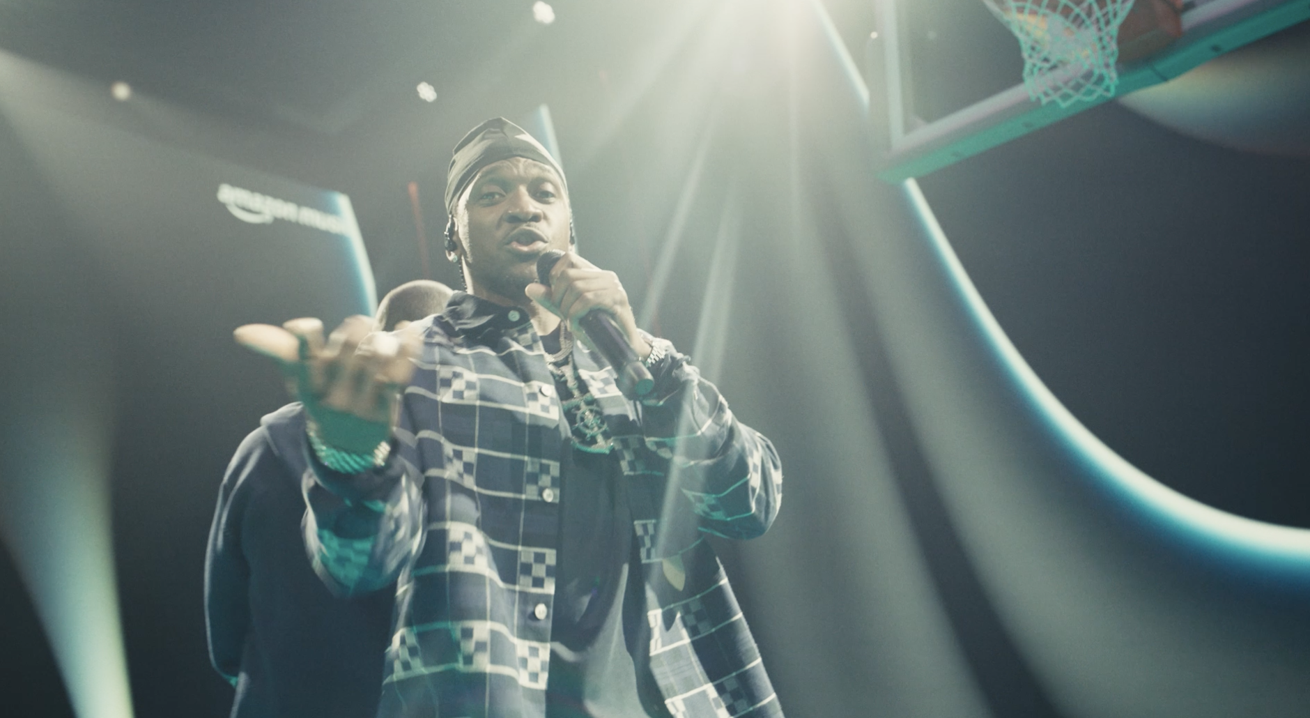 Rapper performing on stage with dramatic lighting and basketball hoop background