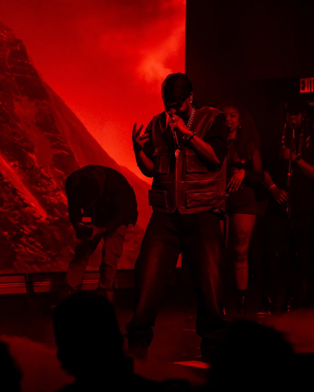 Performer singing passionately on stage with red dramatic lighting