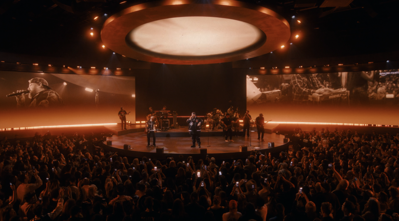 Large music concert with band performing on circular stage to packed crowd