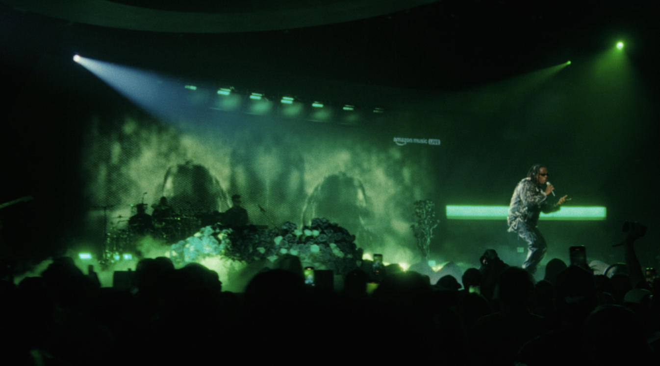 Rapper performs on stage with dramatic green lighting and smoky background