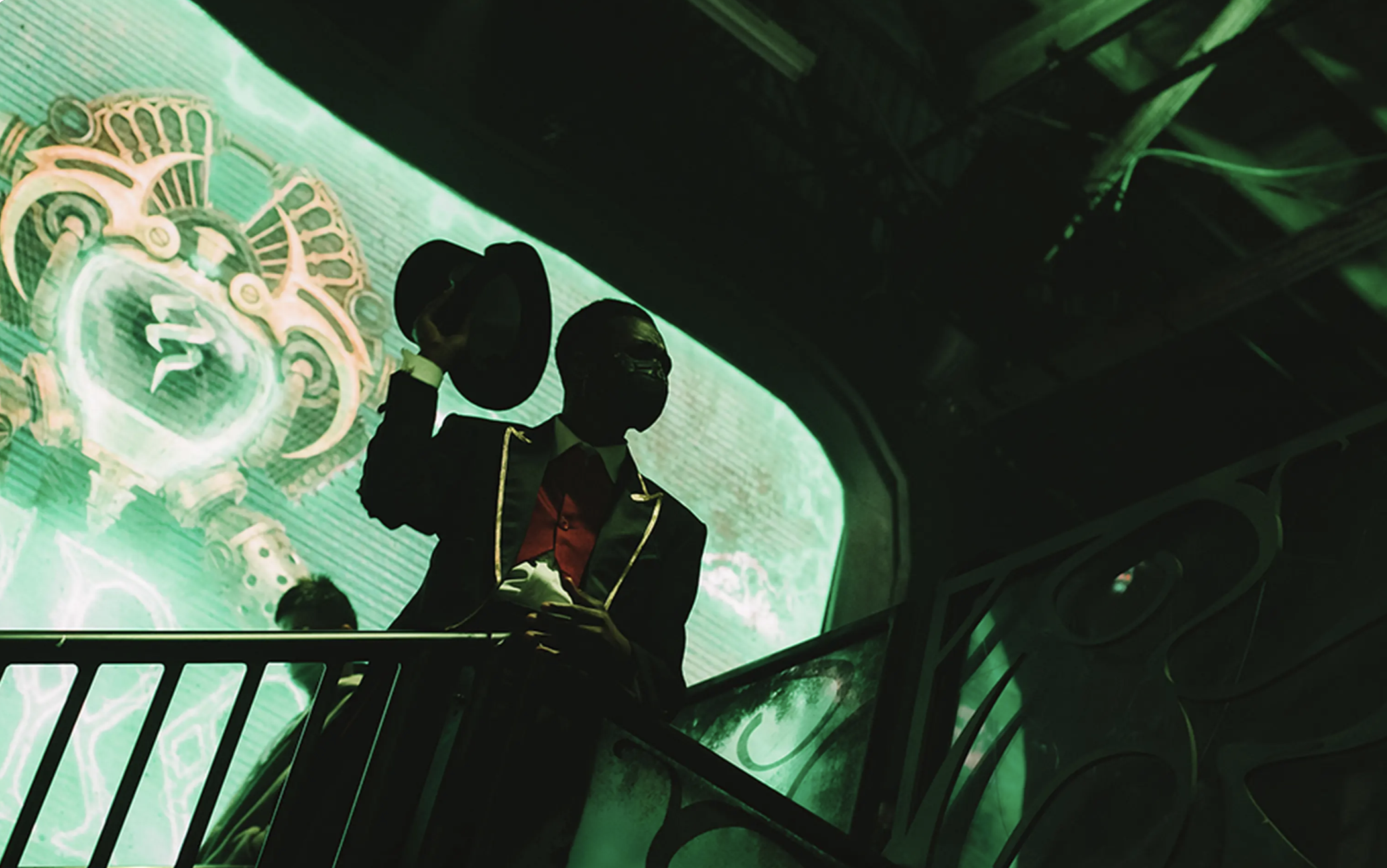 Silhouetted figures on a green-tinted platform with ornate background design