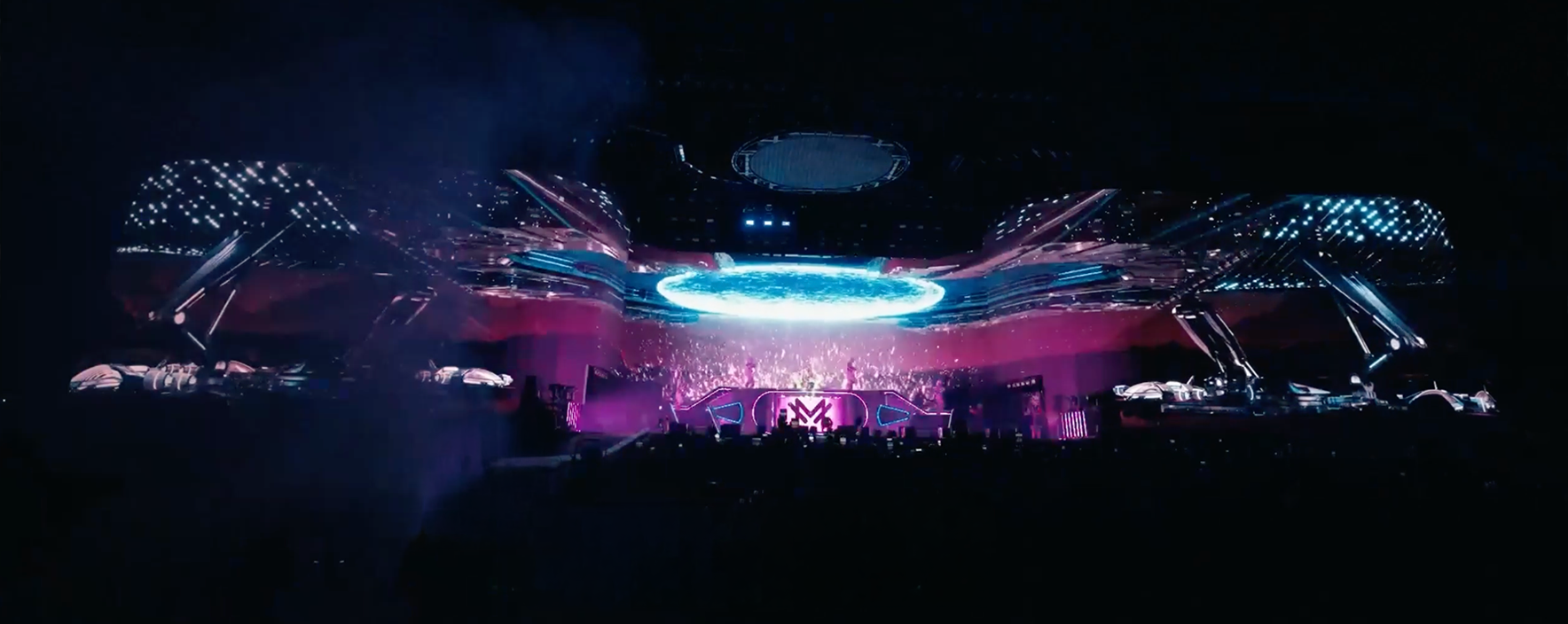Futuristic concert stage with massive glowing circular display and crowded arena