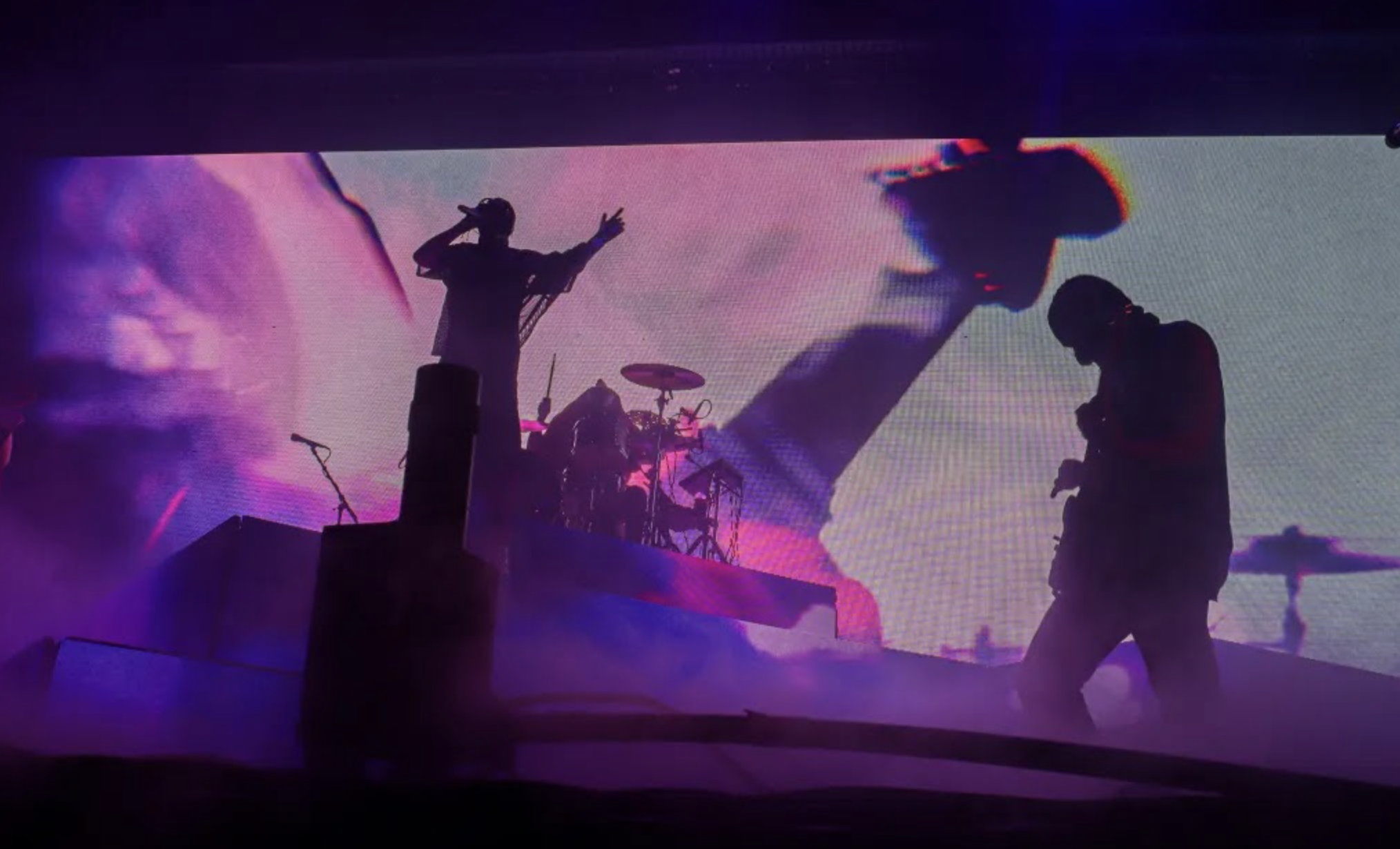 Silhouetted musicians performing on stage with dramatic purple and pink lighting