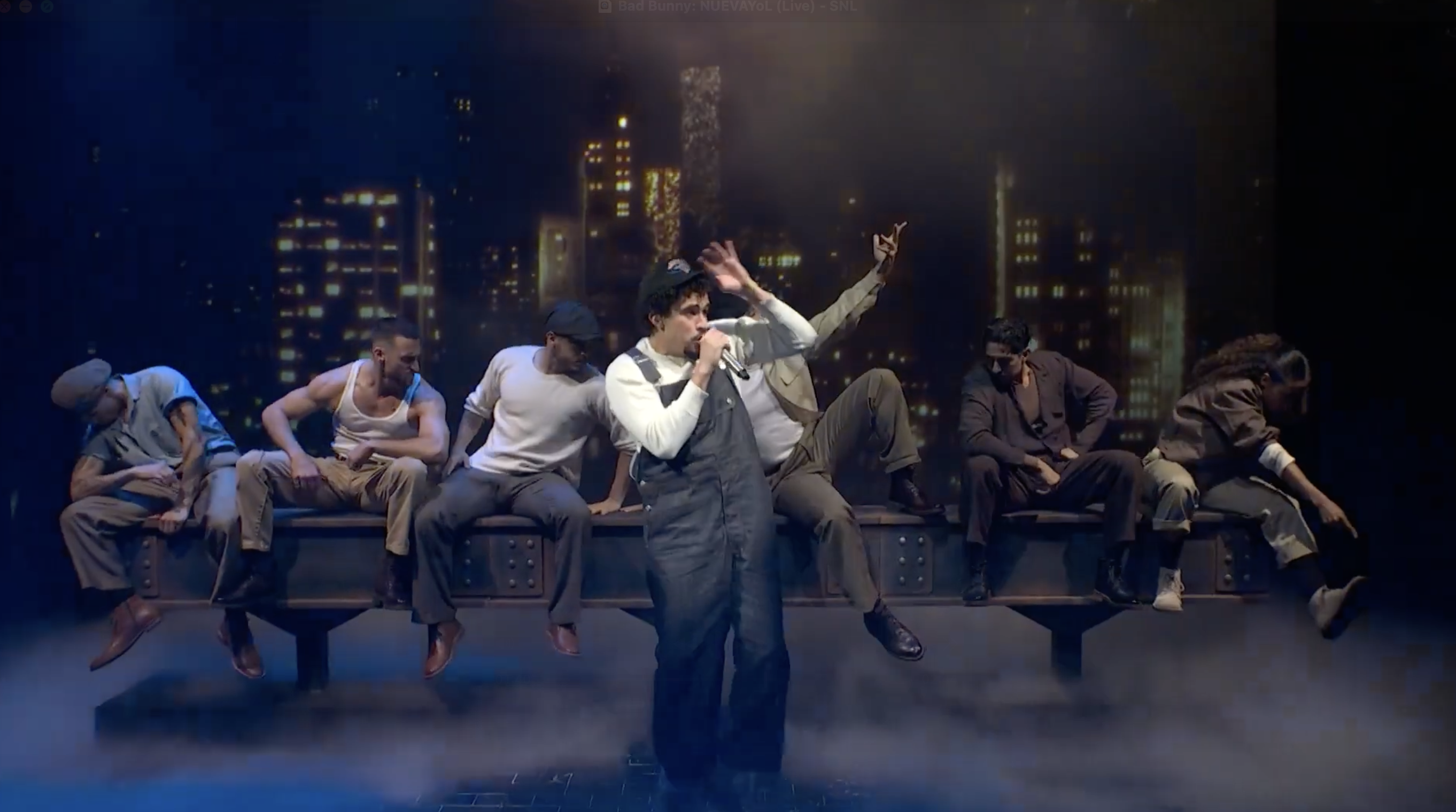 Theatrical performance with singer and dancers on stage, city skyline backdrop