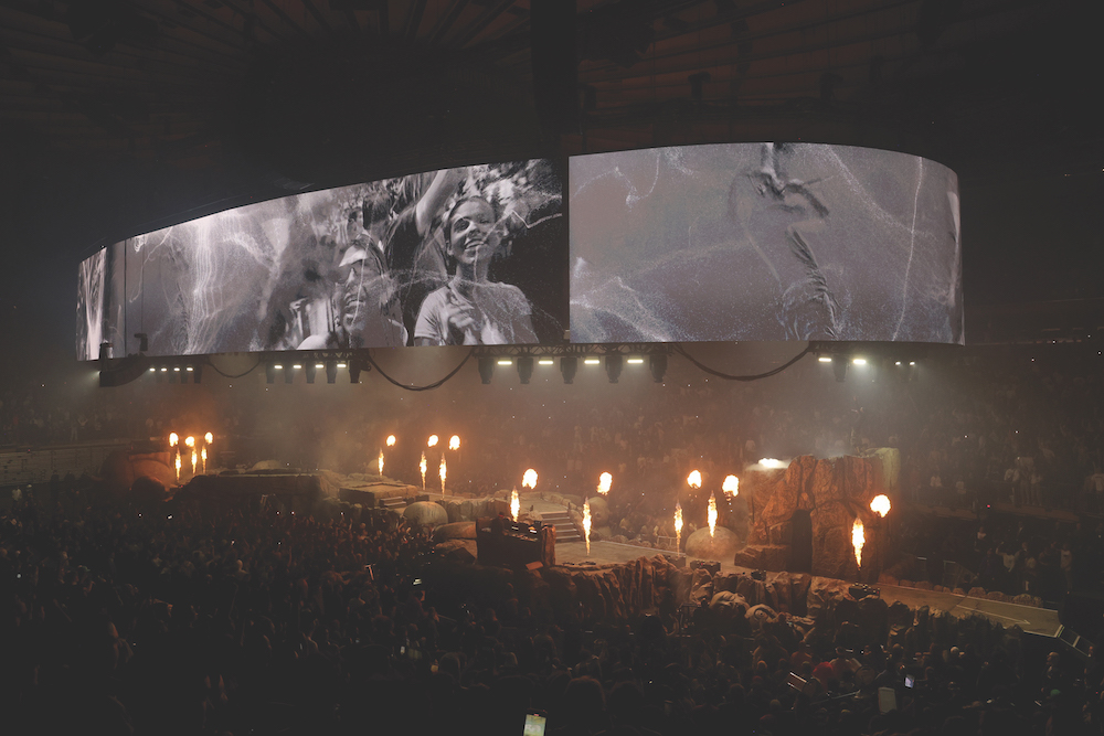 Large concert stage with black and white video screens and flame effects