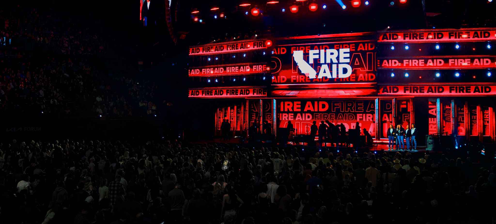 Fire Aid event stage with large crowd and red-lit repeating logos