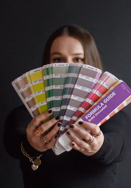 Hannah Hernandez holding up the Pantone color book for CMYK color codes.