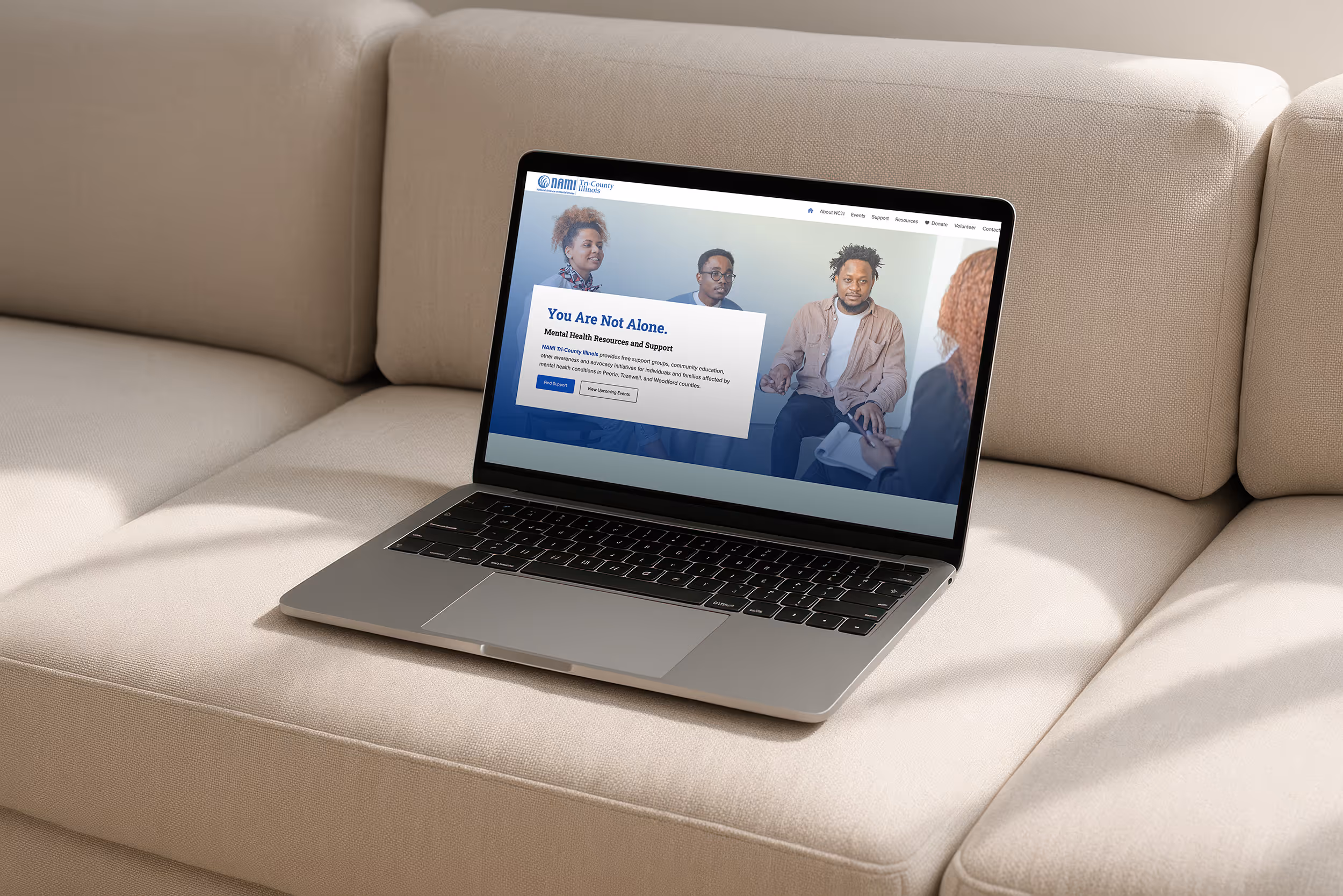 A laptop sitting on a couch opened to the home page for NAMI Tri-County Illinois.