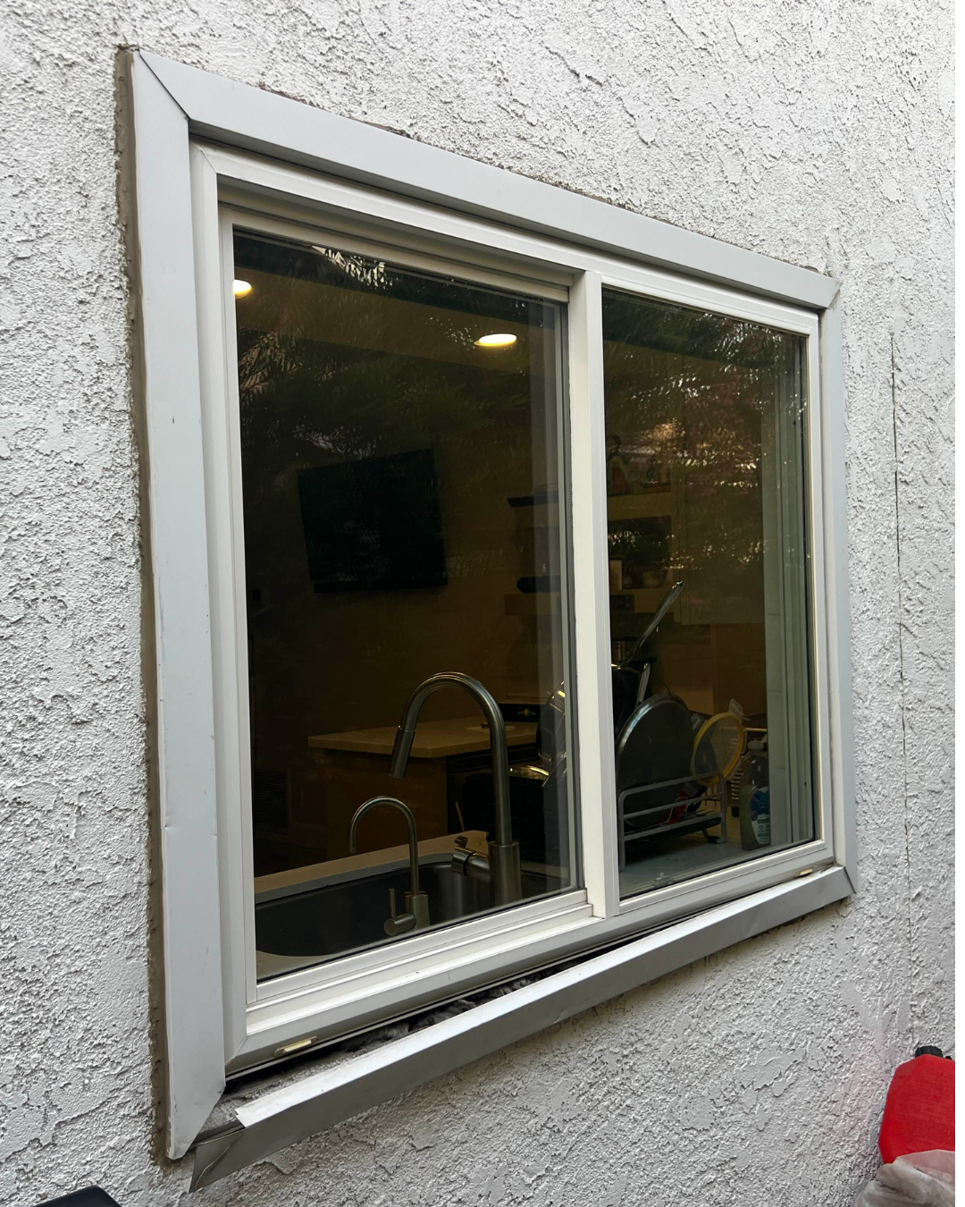 Before: Exterior view of worn sliding window with white frames with visible wear
