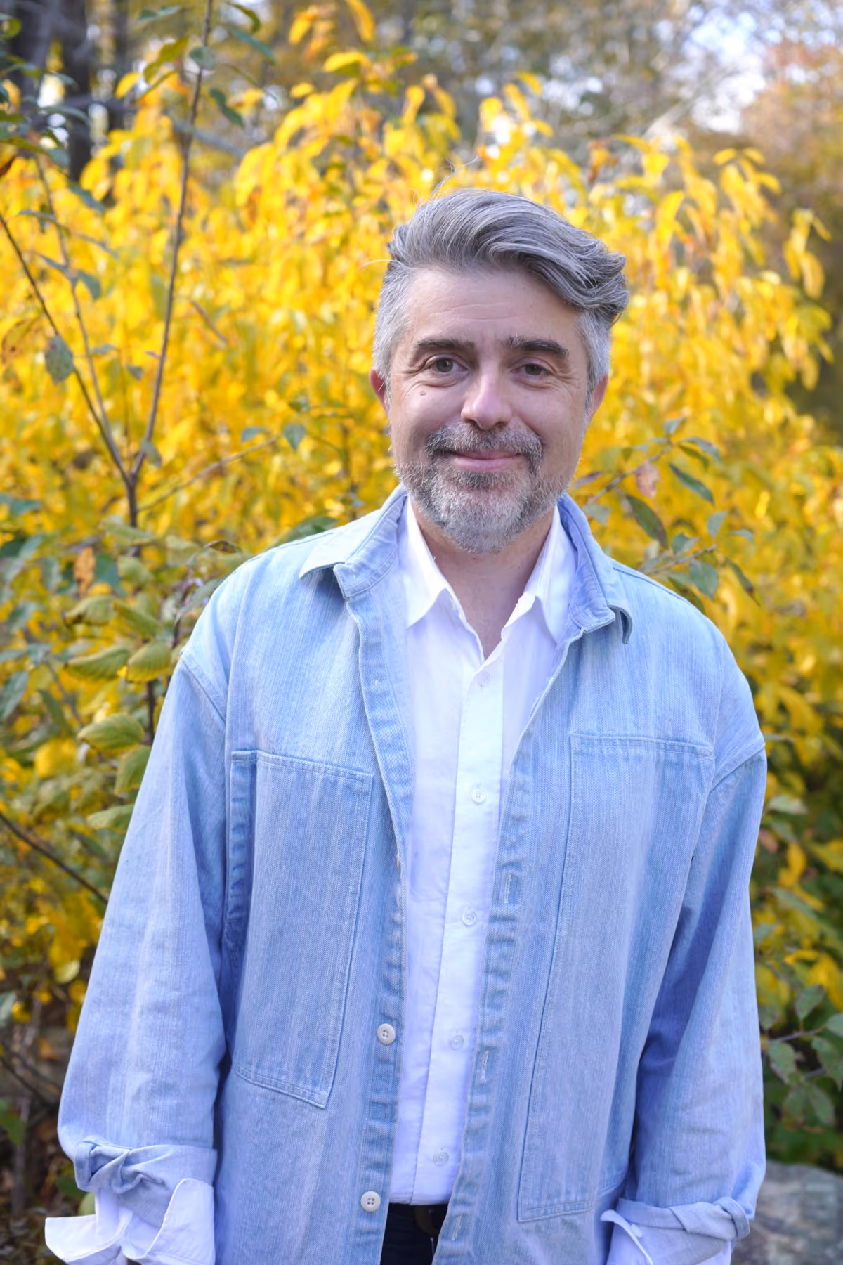 Roddy Schrock, seated outdoors among autumn trees