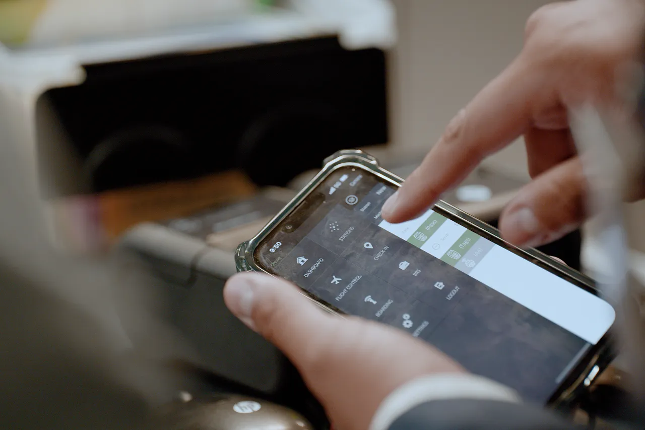 Person using a smartphone with a flight control and dashboard app interface visible.