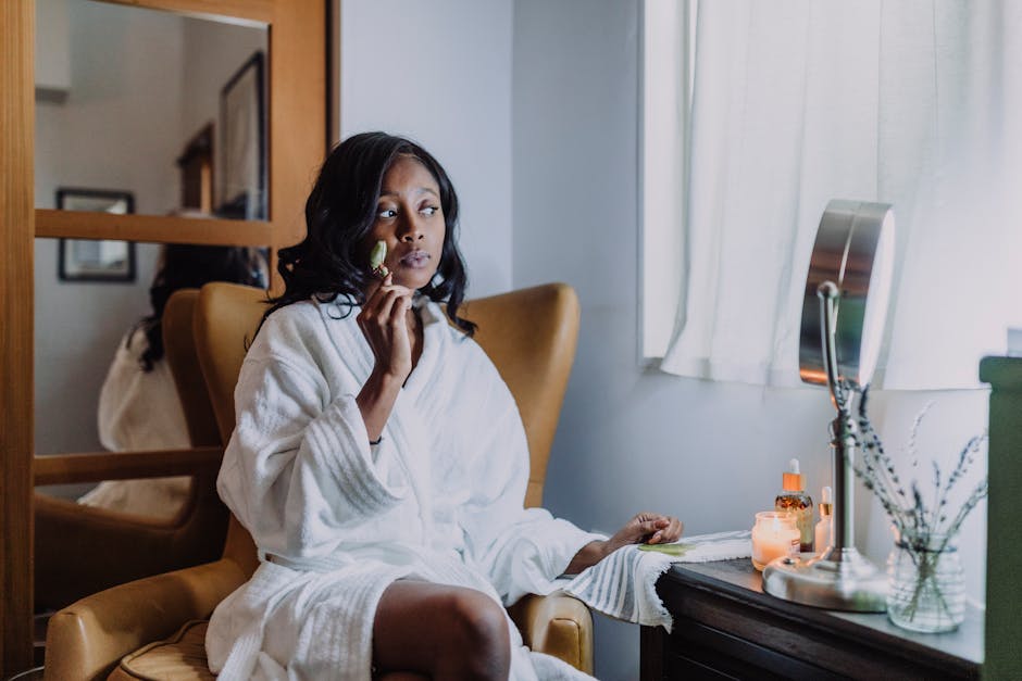 African American woman enjoying a face massage with a jade roller in a cozy room.